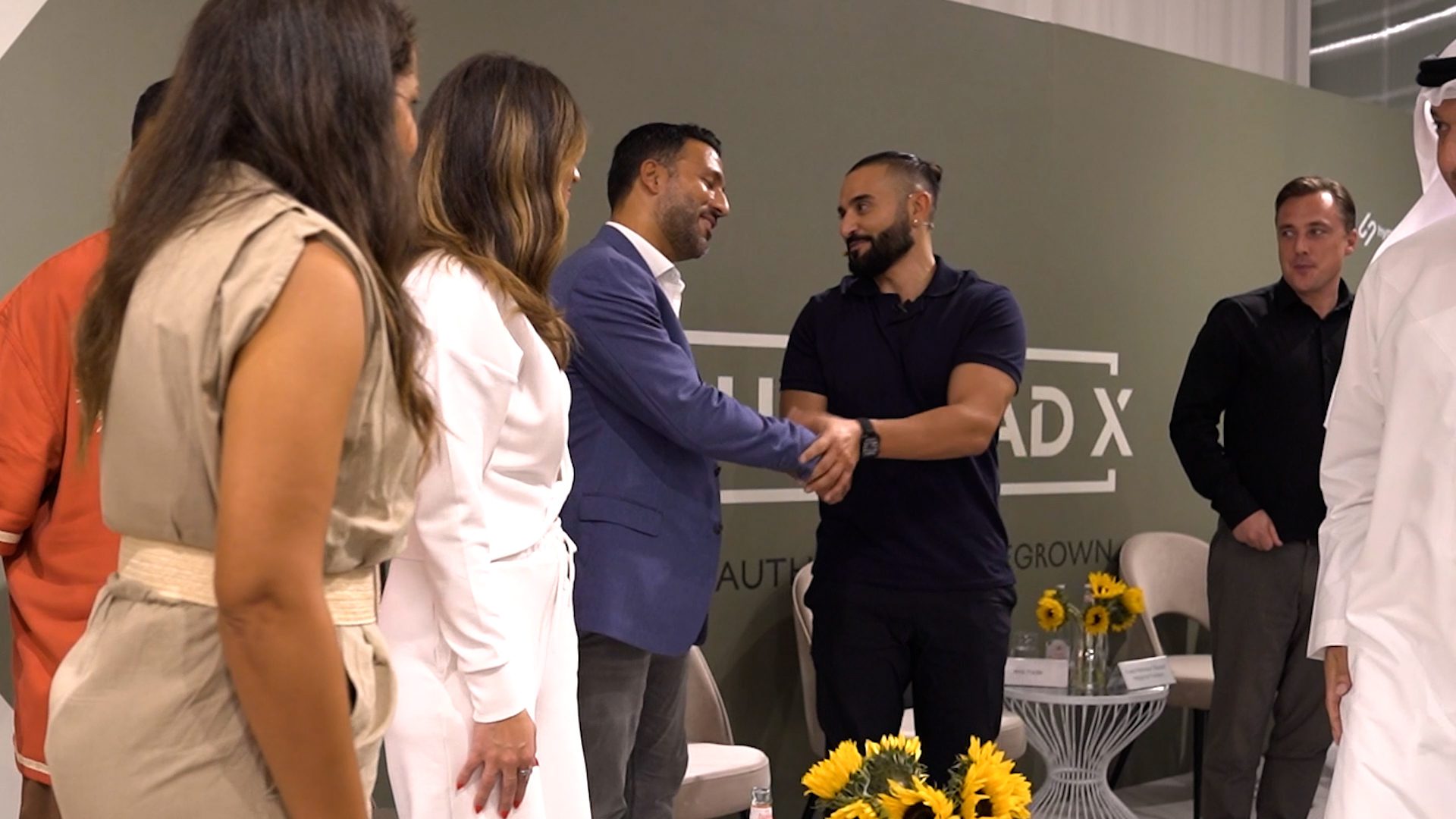 Two guests shaking hands in front of the Launchpad X wall as the store is unveiled.