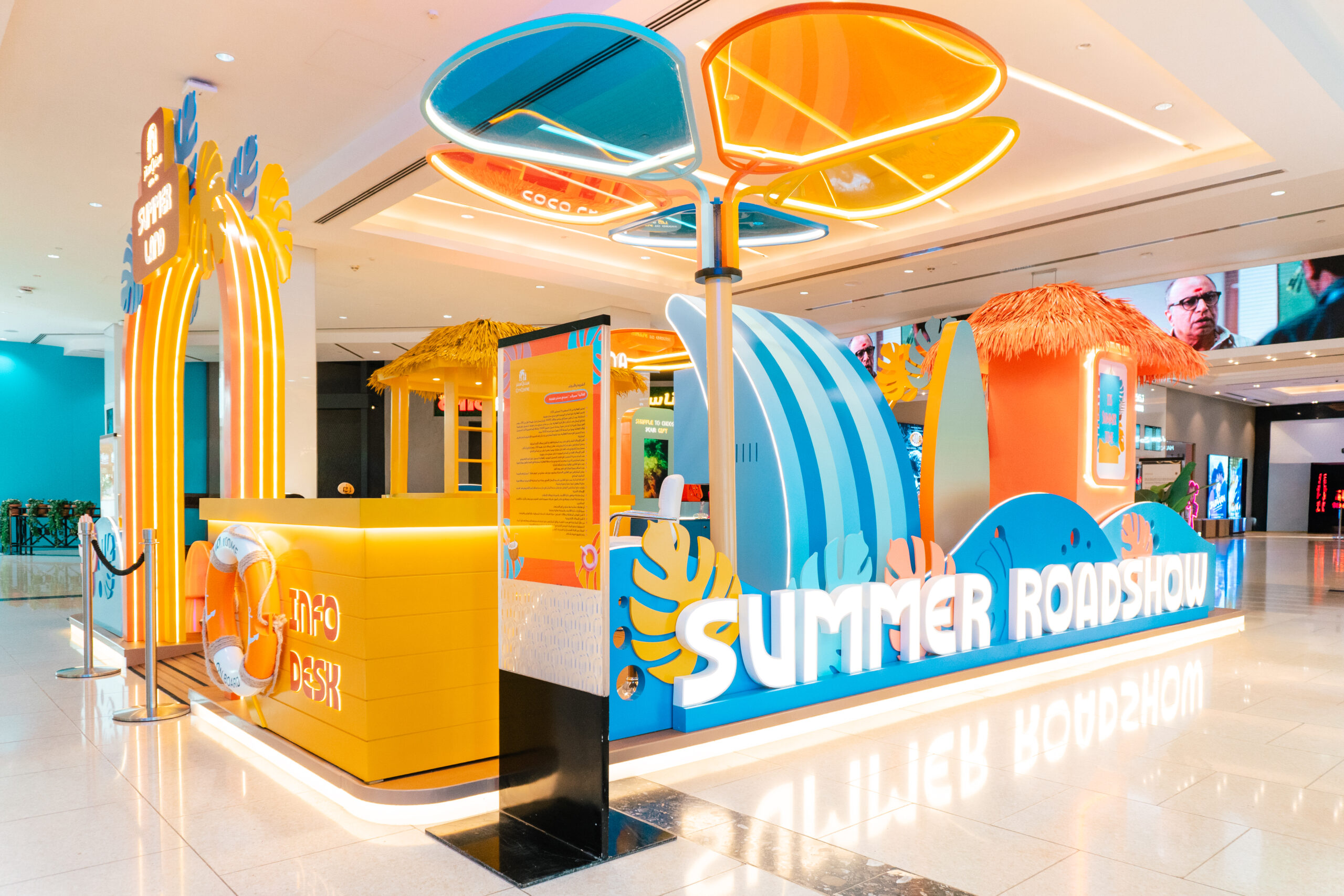 The Summer Roadshow kiosk from the side, its surfboard canopy and thatched roofline above the counter