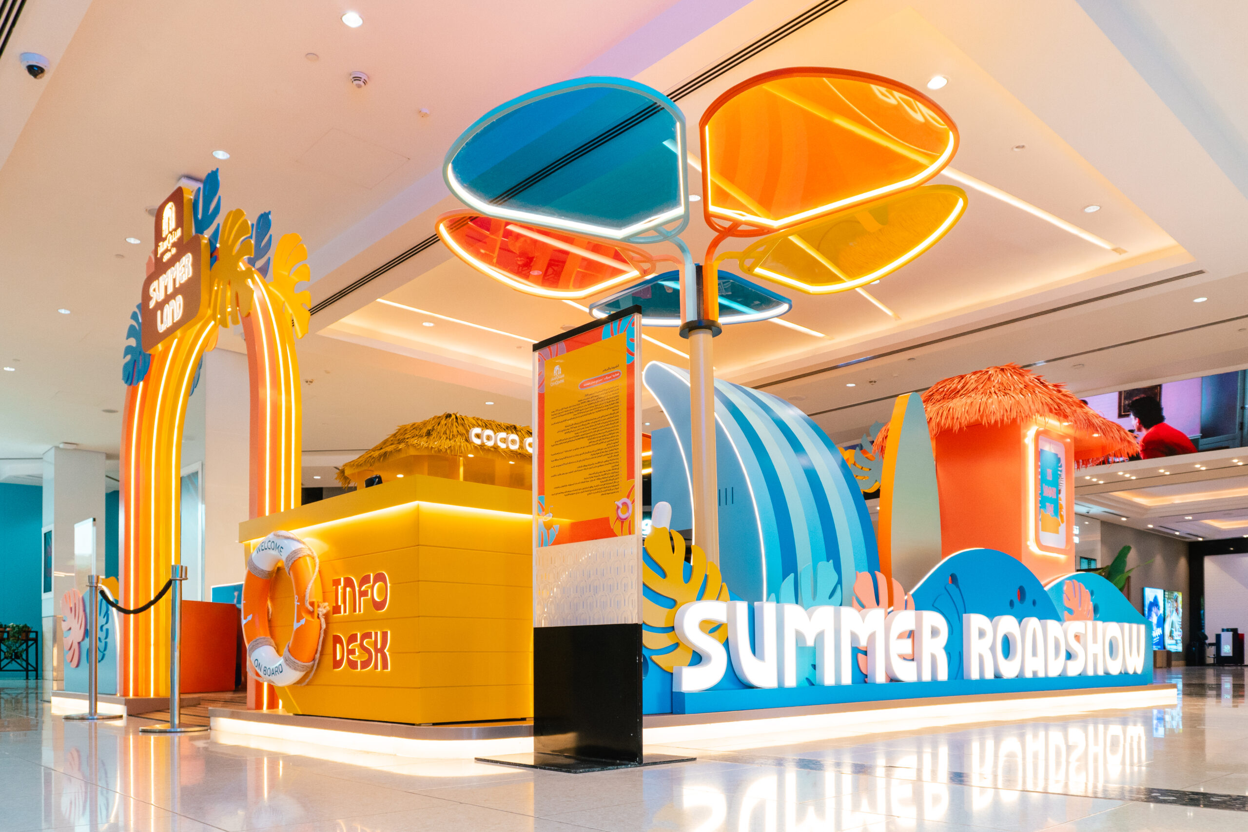 The full Summer Roadshow set in the mall atrium, with its wave backdrop and branded archway