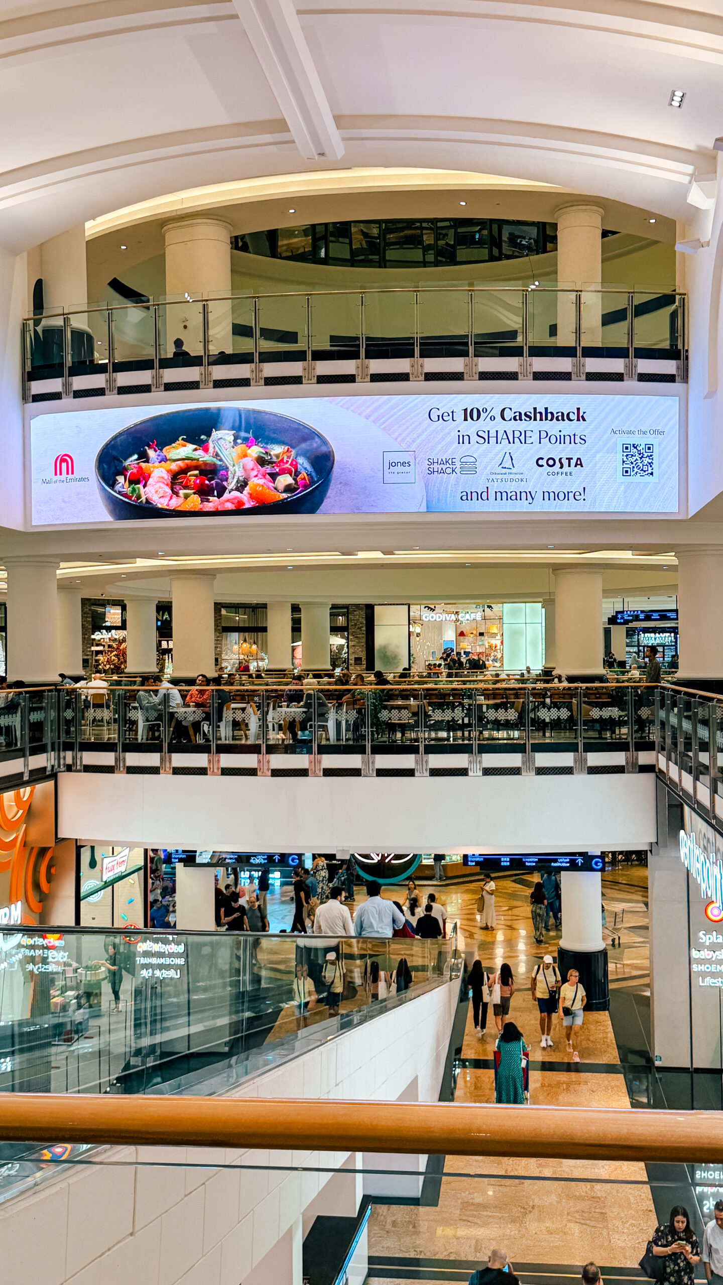 A tall view of the SHARE Points cashback billboard above the food-court balcony and escalators.