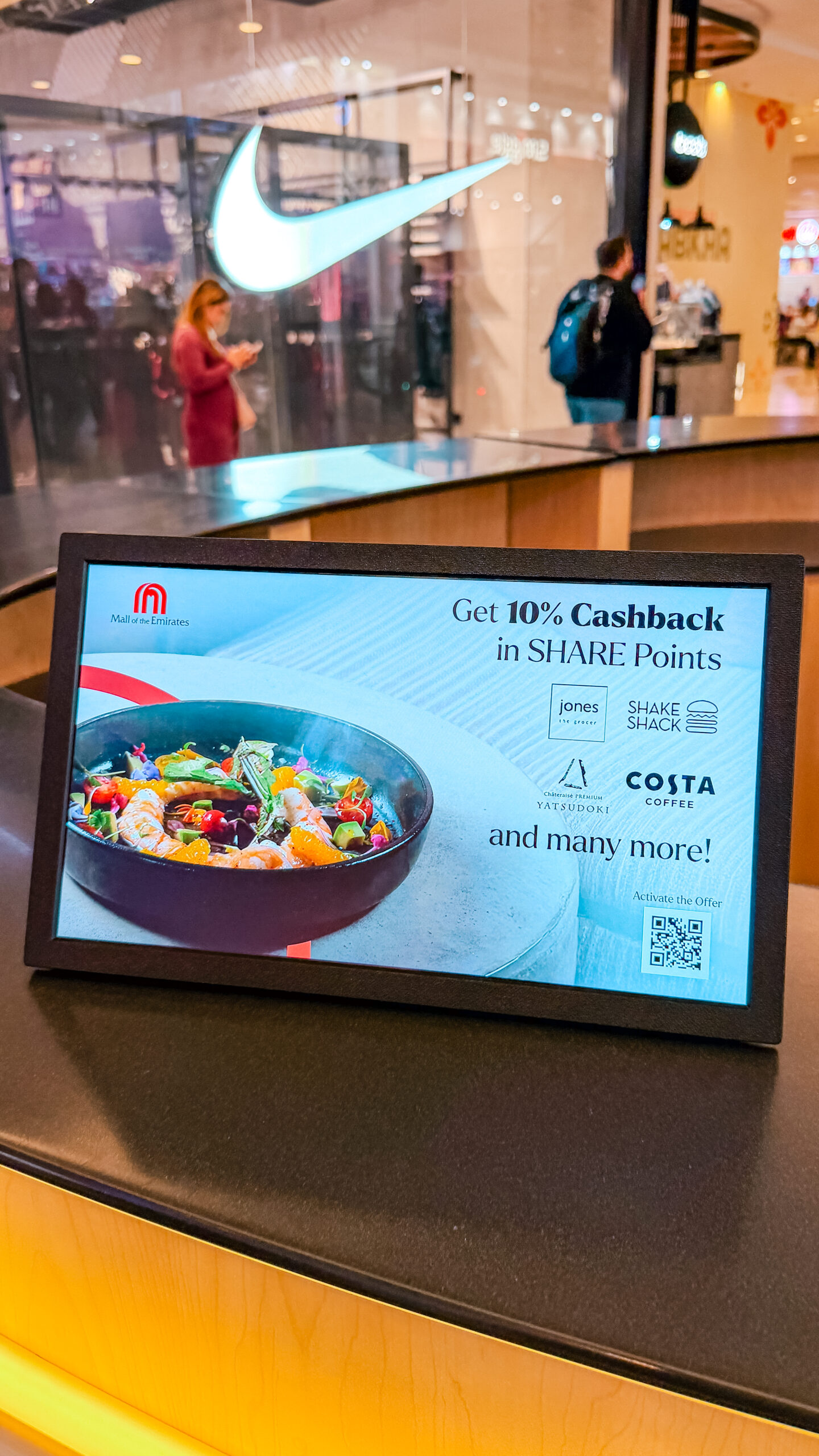 A tabletop screen showing the SHARE Points cashback offer, with the Nike storefront behind.