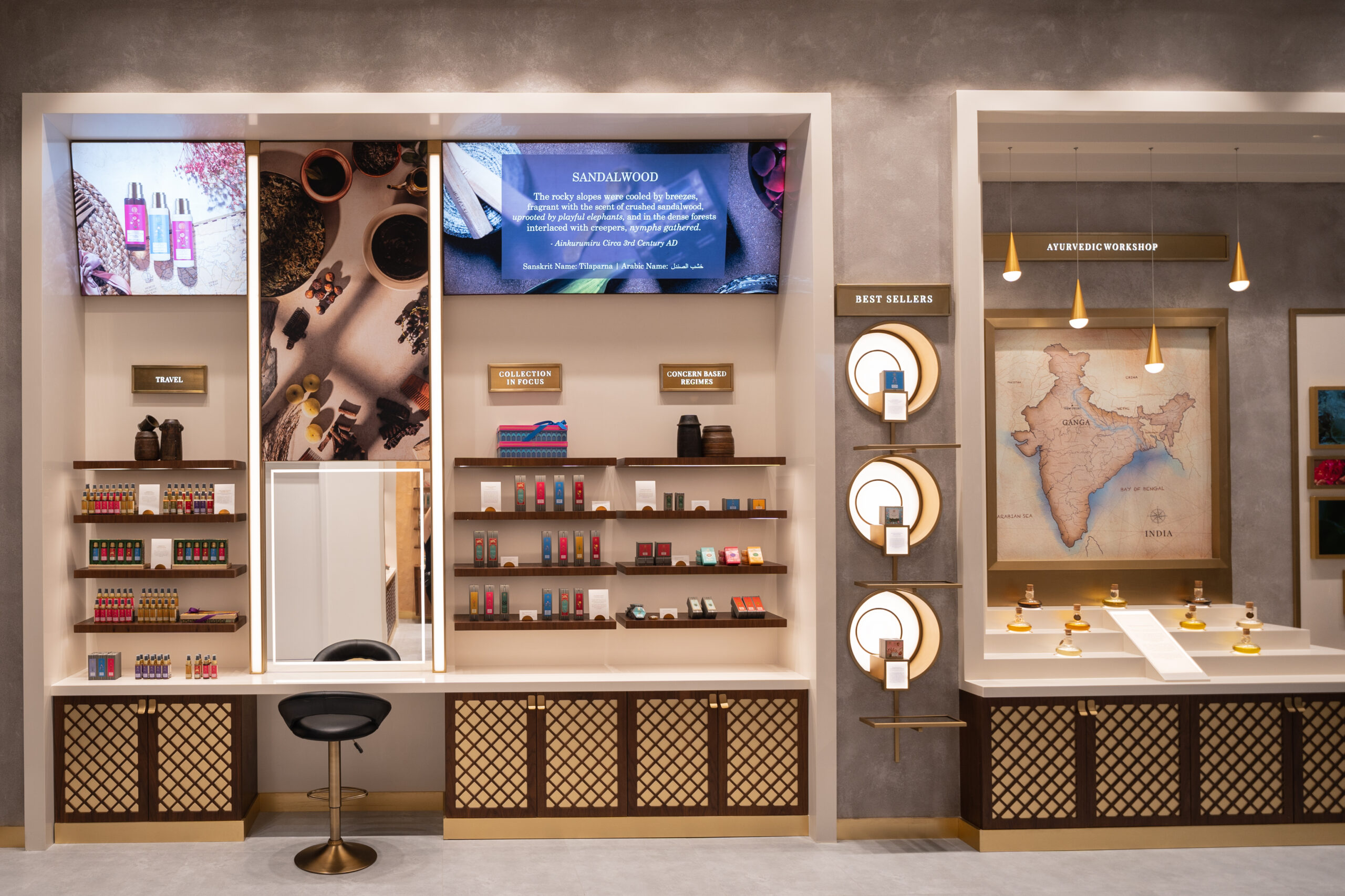In-store consultation counter beside the Ayurvedic Workshop wall, with a sandalwood ingredient screen and a map of India
